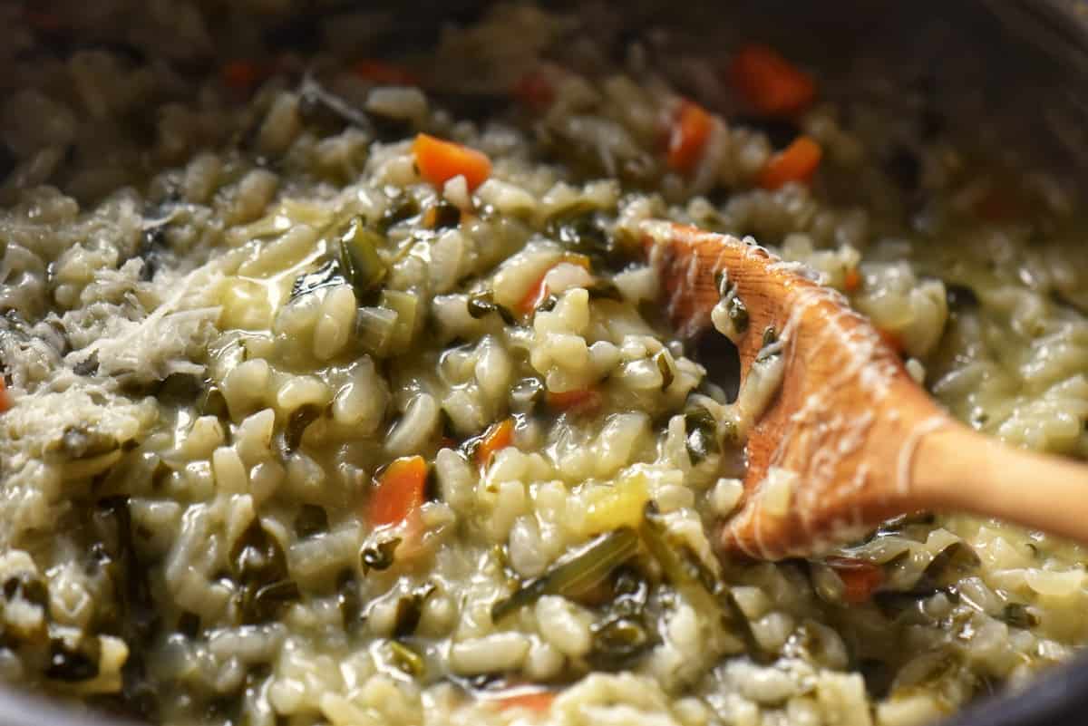 A close up shot of a risotto spoon stirring a creamy risotto. 