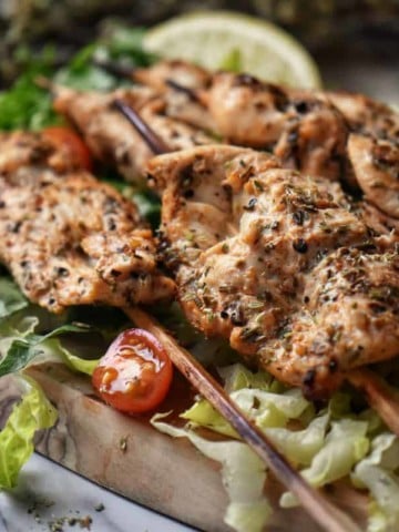 Skewers of chicken spiedini on a wooden board.