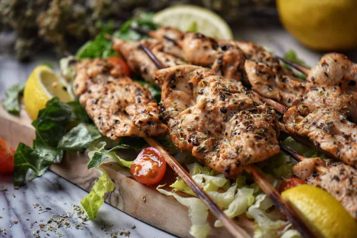 Skewers of grilled chicken on a wooden board.