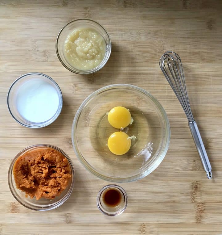 The measured liquid ingredients in small bowls to make chocolate chip pumpkin muffins.