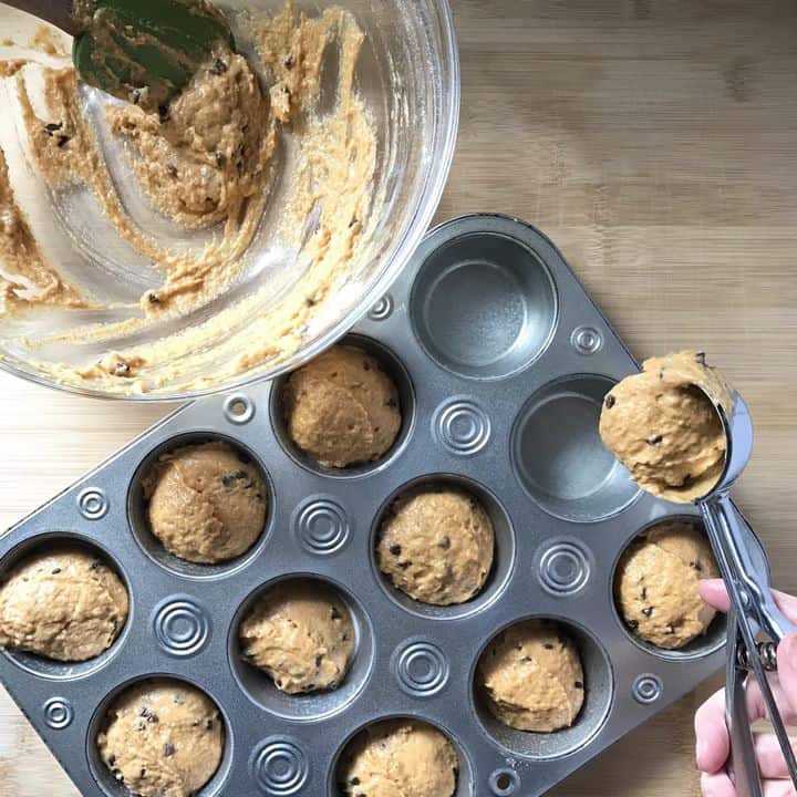 The muffin batter is being portioned in the muffin tray with a disher.