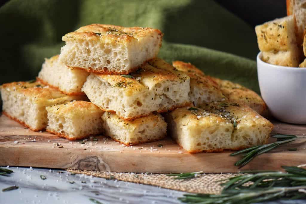 Square pieces of a Italian Focaccia Recipe on a wooden board.