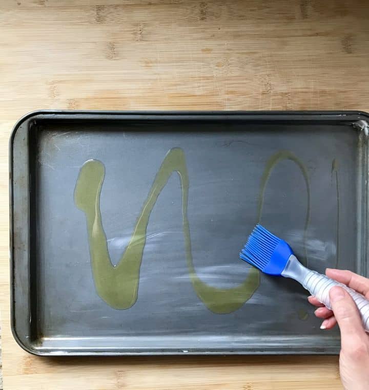 Olive oil is brushed on a rimmed sheet pan ensuring a crispy bottom for the focaccia.