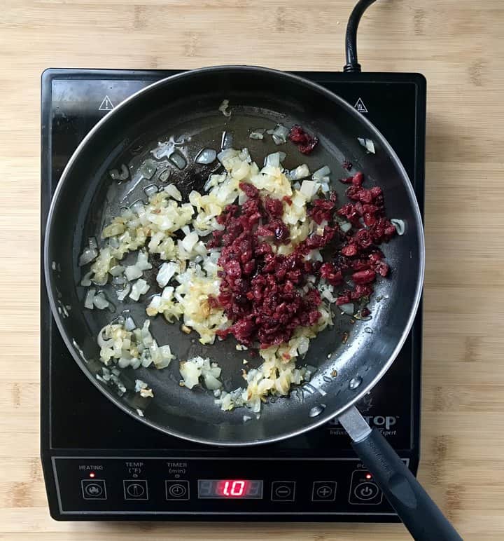 Chopped cranberries and sauteed shallots in a pan.