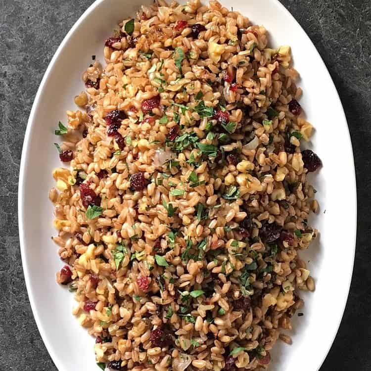 A colorful farro salad in a white serving bowl. 