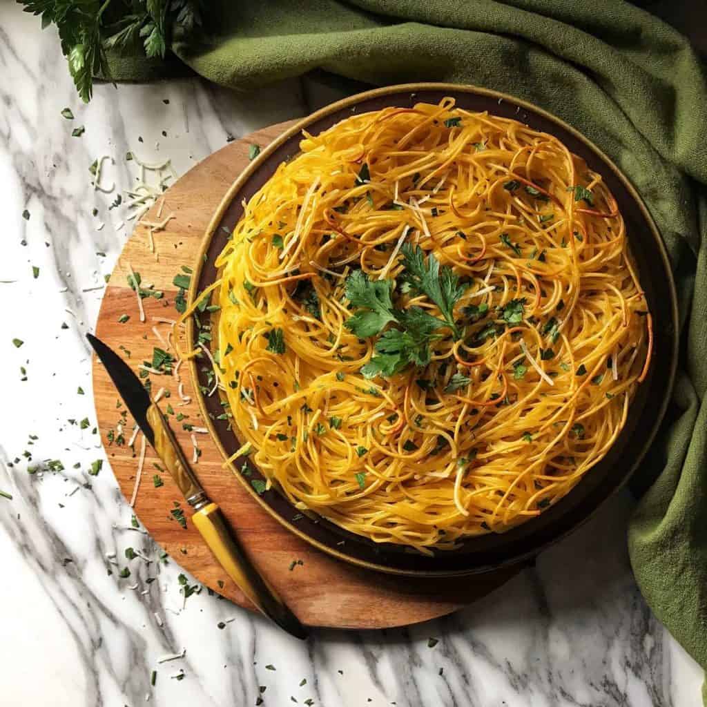 A round platter of spaghetti pie on a wooden board.