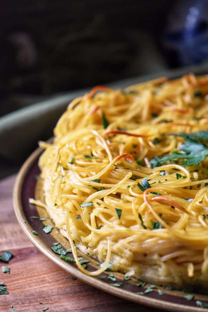 Baked spaghetti pie in plated and topped with fresh Italian parsley.