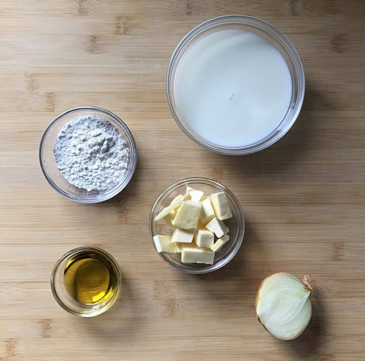 The ingredients to make the bechamel sauce on a wooden counter.