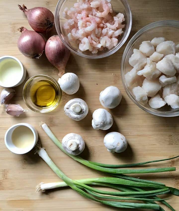 Some of the ingredients to make Coquilles St-Jacques are on a wooden table.