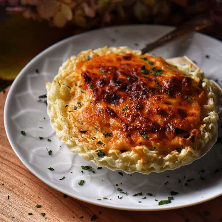 Coquilles St-Jacques set in a white plate on a wooden surface.