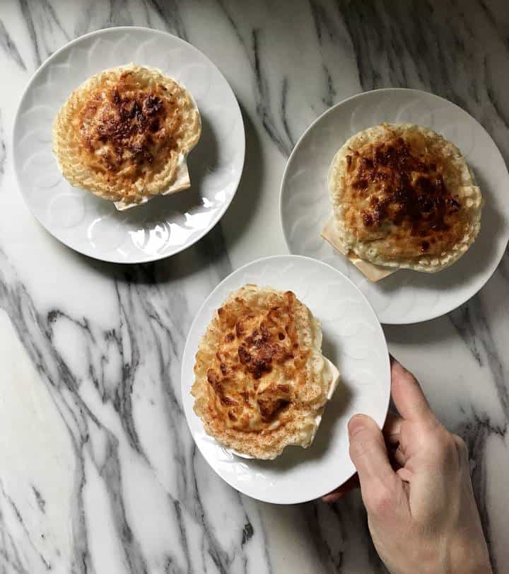 A plate holding Coquilles St-Jacques held on its side.