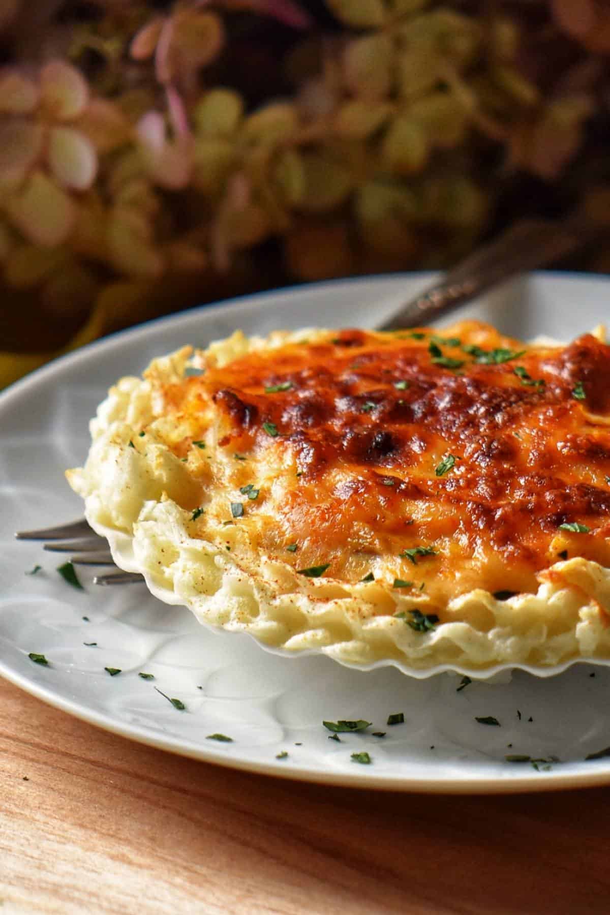 A scallop shell is filled with the French classic appetizer, Coquilles St-Jacques.
