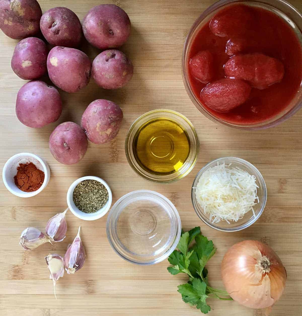 The ingredients to make this Italian Potato Recipe are on a wooden board.