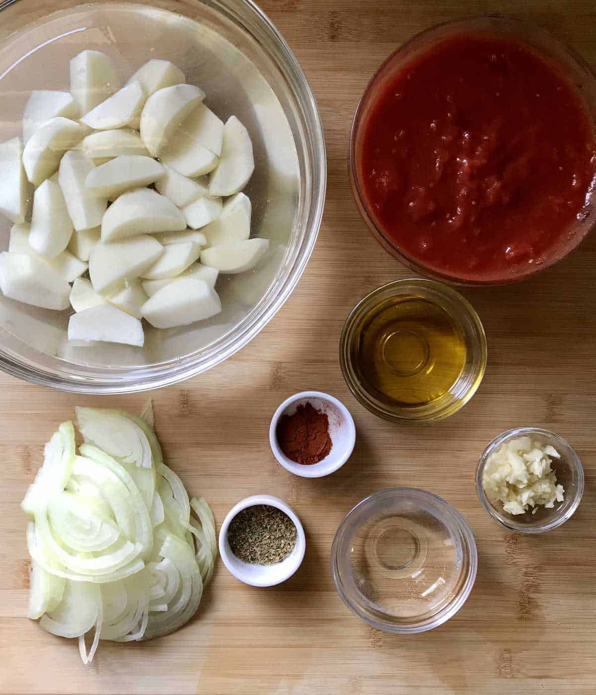 The prepped ingredients to make the Italian Potato Recipe are prepped and placed on a wooden board.