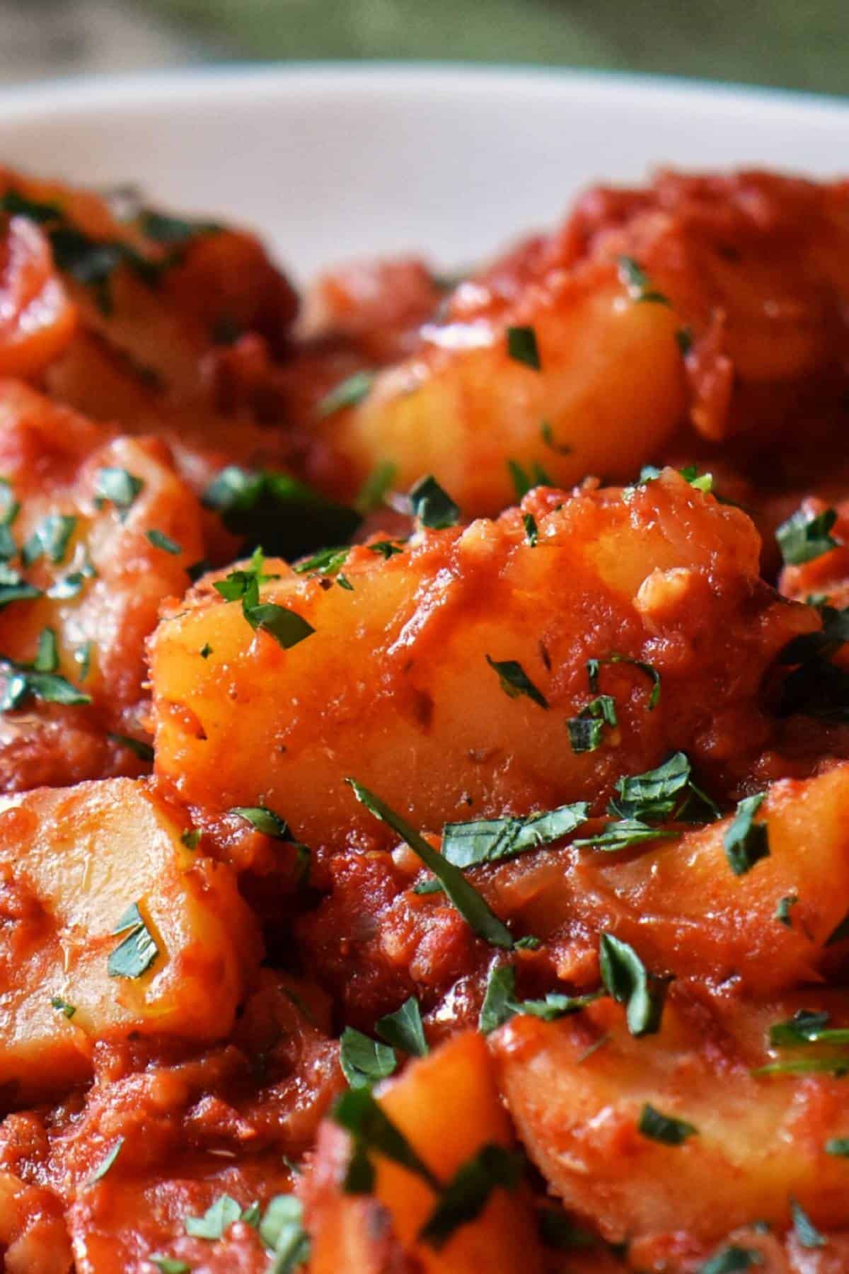 Potato wedges smothered with tomato sauce and herbs.