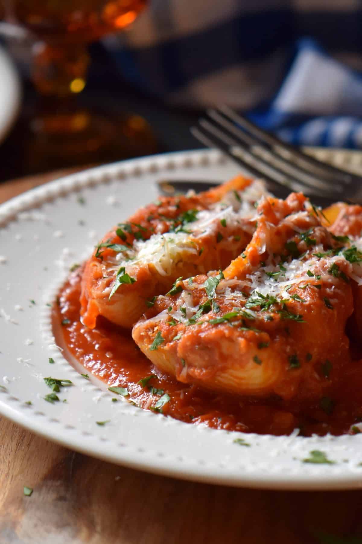 Italian Stuffed Shells in a white plate with lots of tomato sauce.