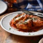 Baked Italian pasta shells on a white dinner plate dusted with cheese.