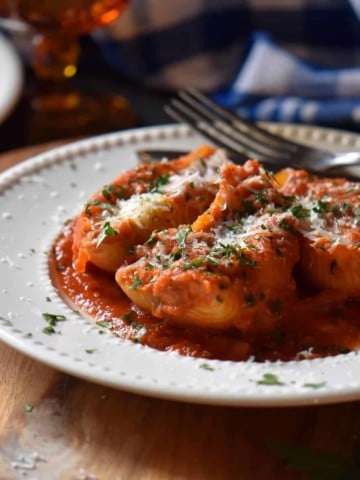 Baked Italian pasta shells on a white dinner plate dusted with cheese.