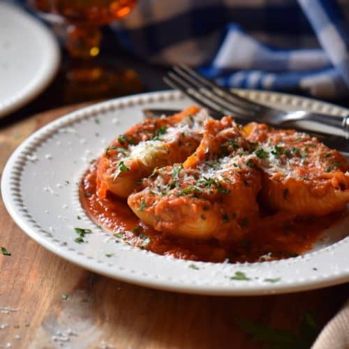 Baked Italian pasta shells on a white dinner plate dusted with cheese.