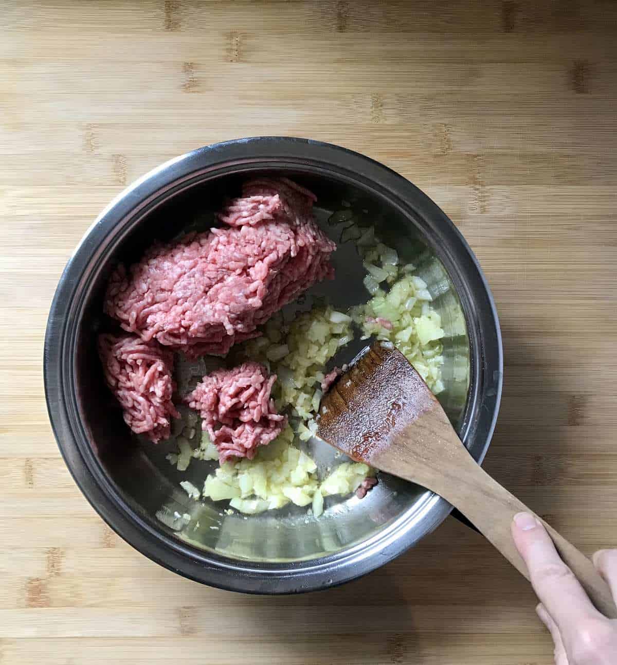 Lean minced meat is sauteed with onions and garlic in a pan.
