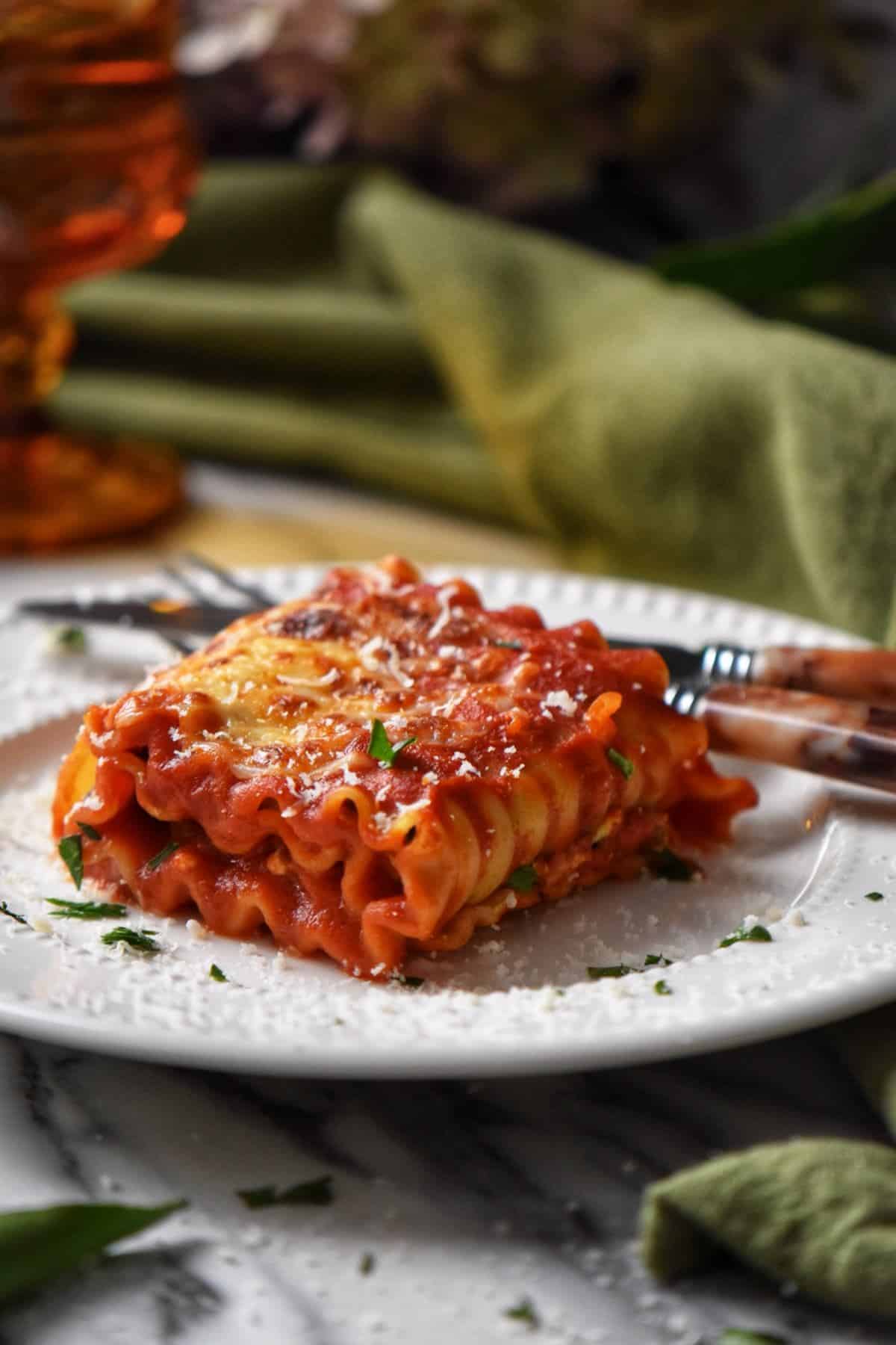 A single lasagna roll up in a white plate.