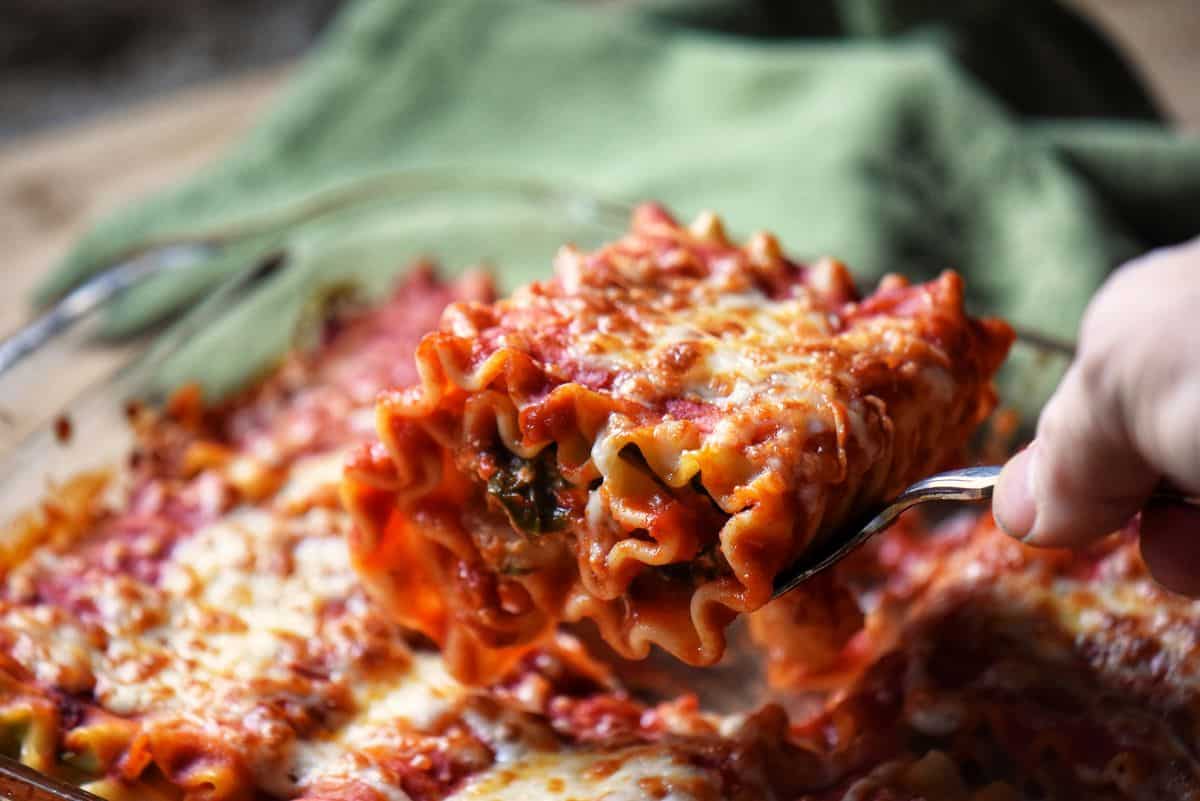 A lasagna roll up being lifted from a pan.