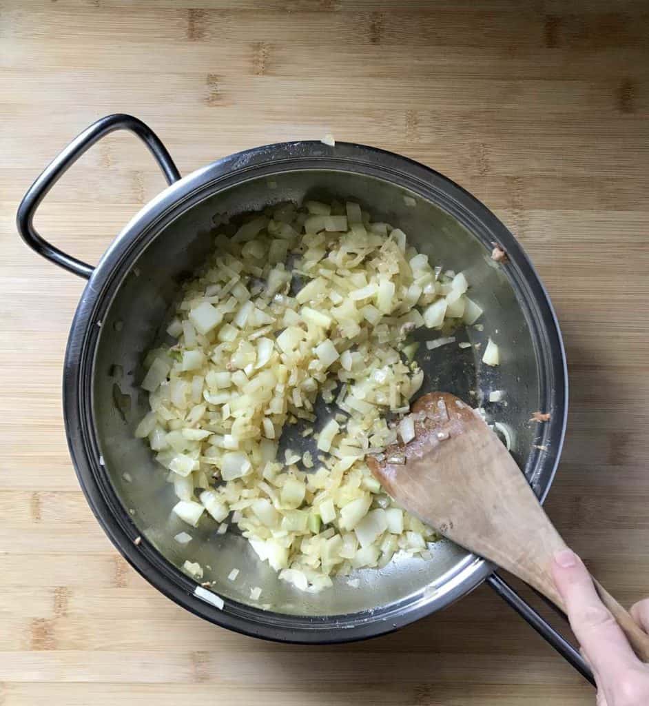 Diced fennel and sweet onion in a saucepan being sauteed.