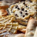 A cannoli dip with chocolate chips surrounded by pizzelle.