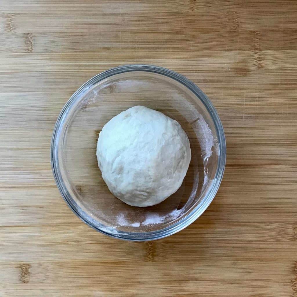 A ball of dough in a glass bowl.
