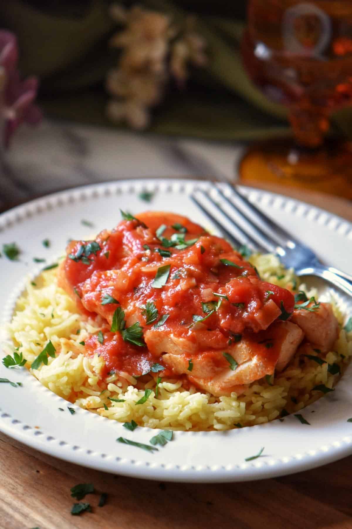 A piece of Italian cod topped with tomato sauce over a bed of rice.