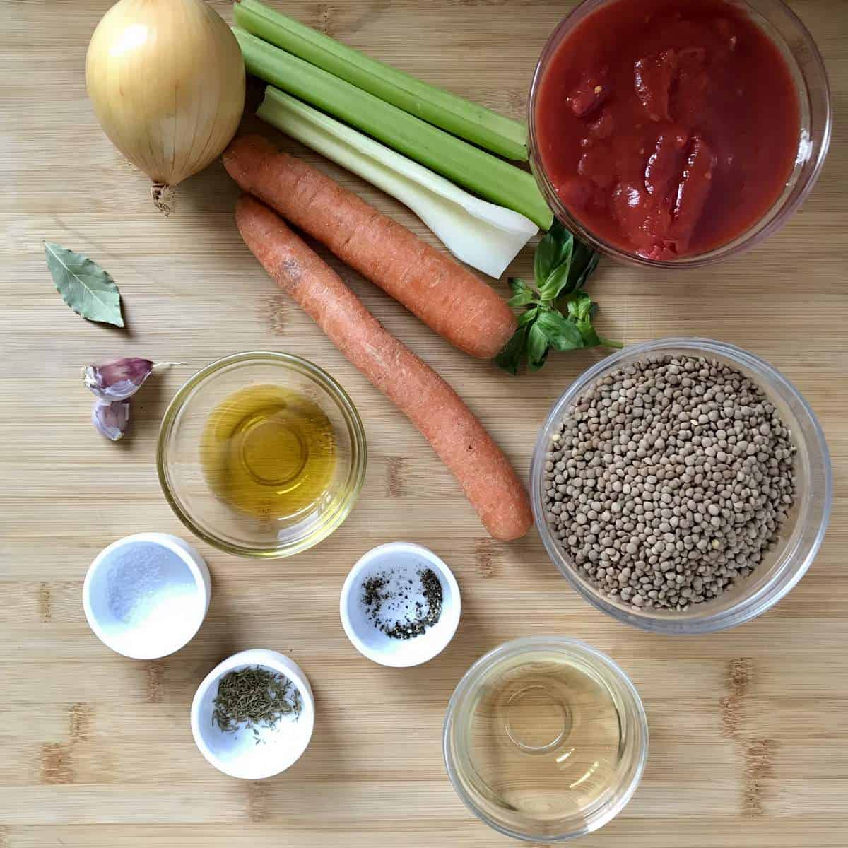 The ingredients needed to make lentil soup on a wooden board.