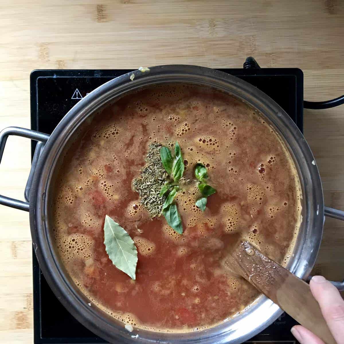 Herbs and a bay leaf added to the pot of soup.