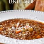 Lentil soup in a white bowl garnished with grated cheese.