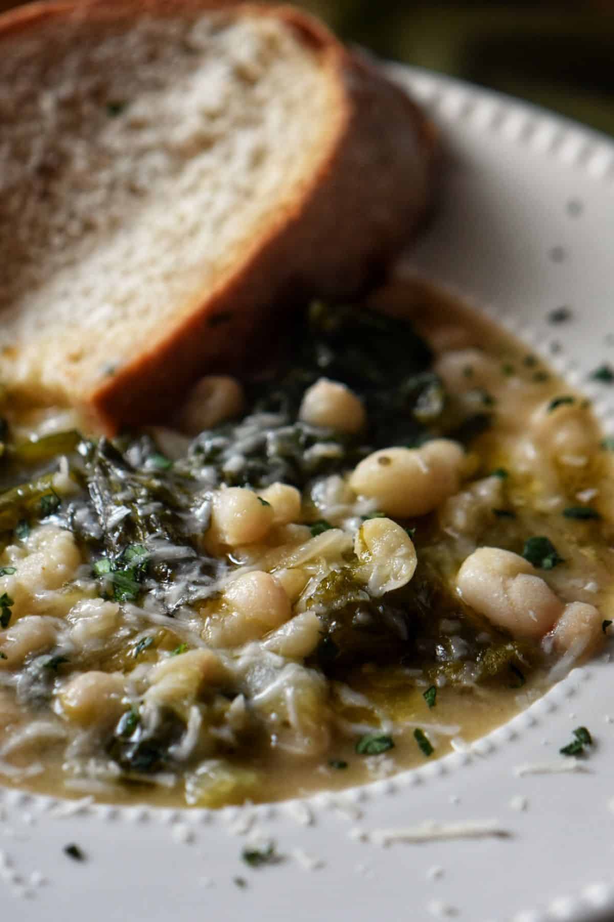 Escarole and white bean soup in a white bowl.