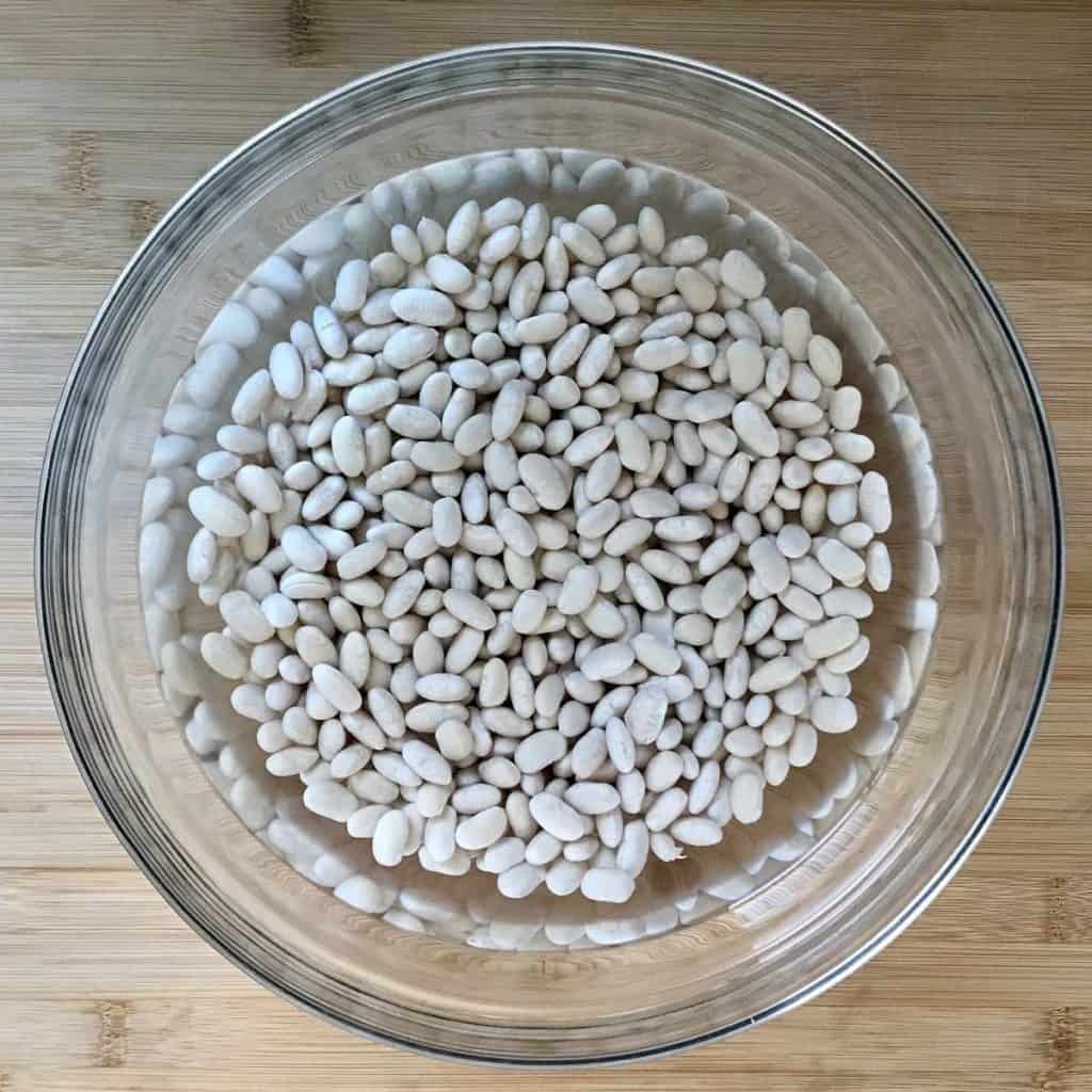White beans soaked in a large bowl.