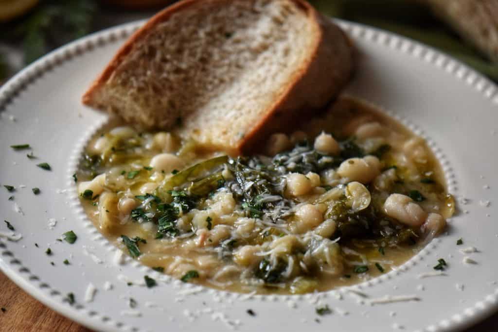 A bowl of beans and greens garnished with chopped parsley.