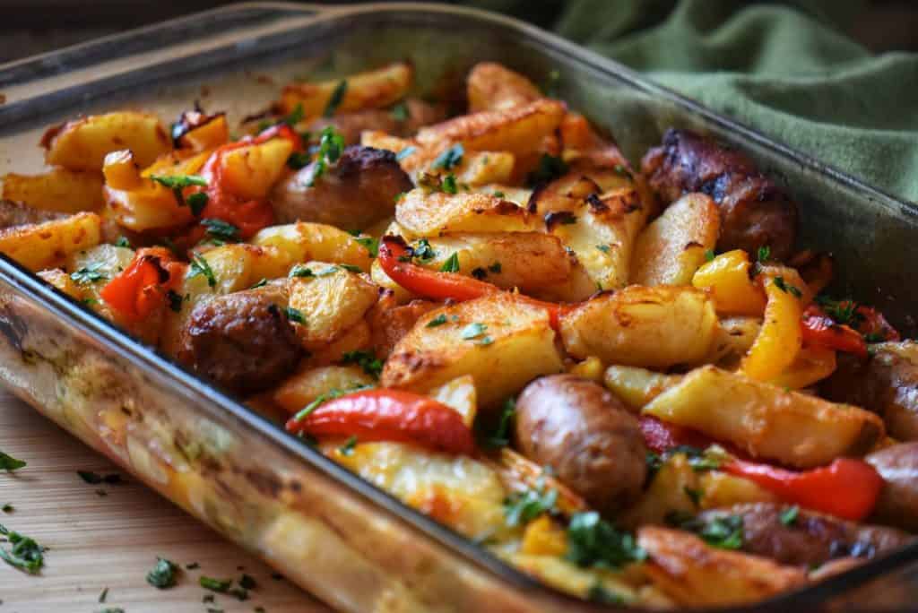 Chopped Italian flat leaf parsley sprinkled over a dish of sausages and potatoes.