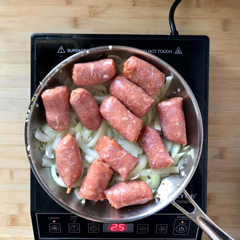 Italian sausage and onions in a skillet.