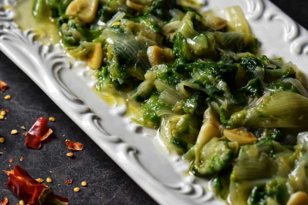 Cooked greens in a white serving dish.