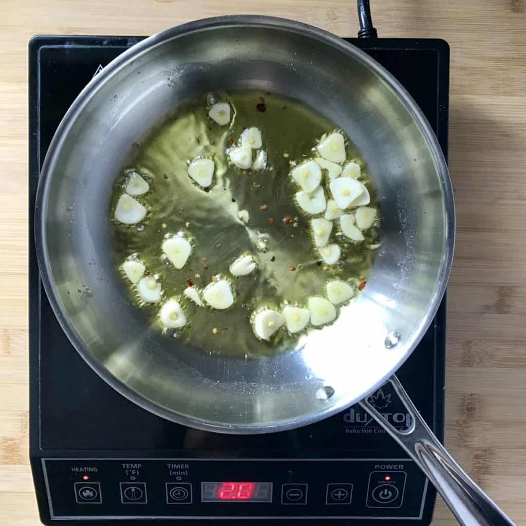 Sliced garlic sauteed in a pan.