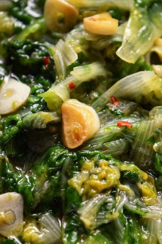 A close up photo of escarole with garlic.