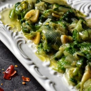 Sauteed Escarole with lots of garlic and red pepper flakes on a white platter.