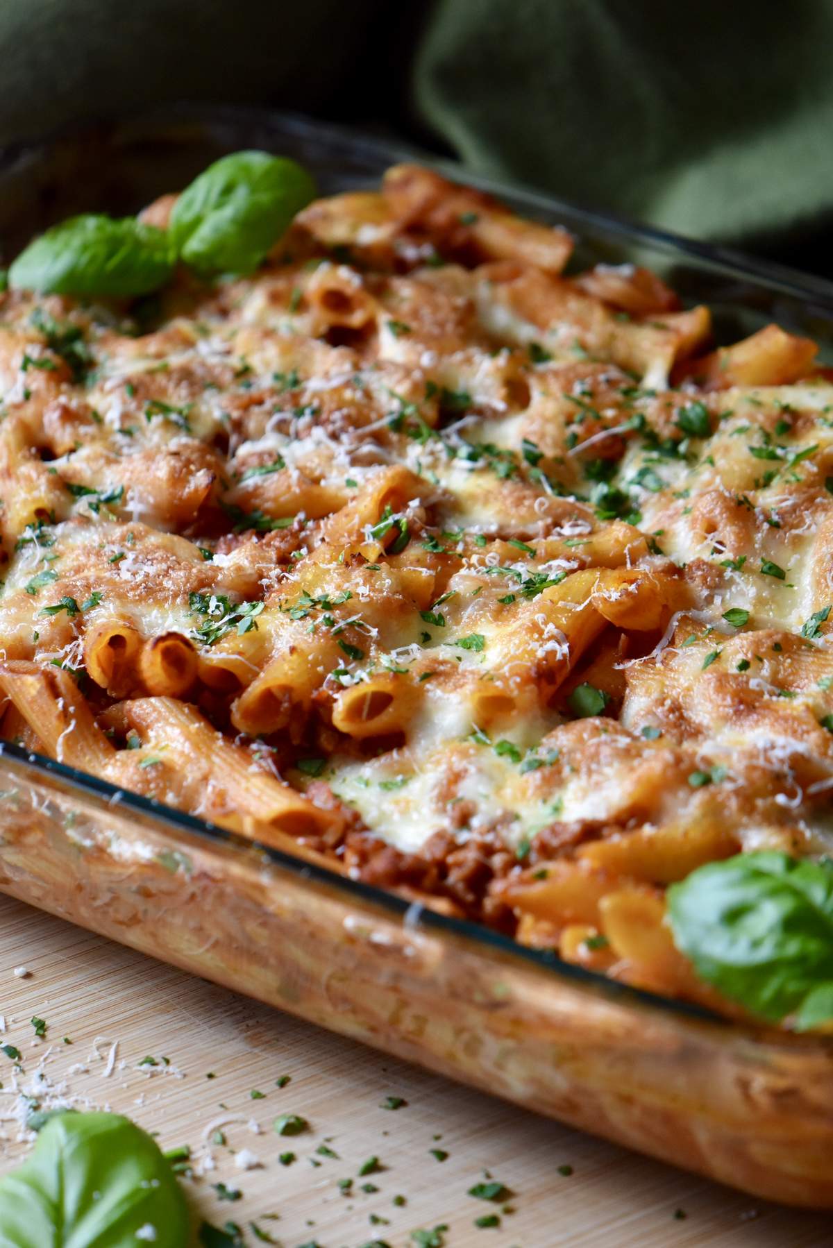 Basil leaves top a cheesy baked pasta dish. 