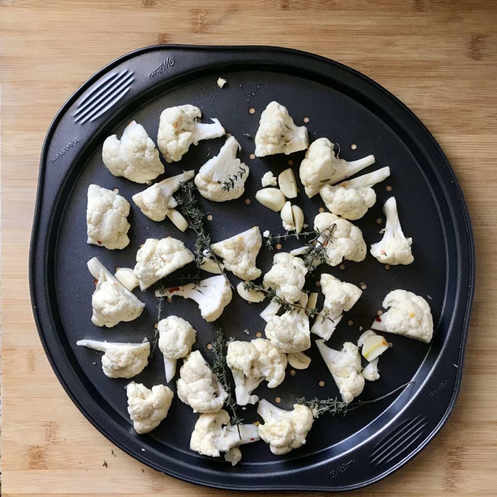 Seasoned cauliflower florets in a pan.
