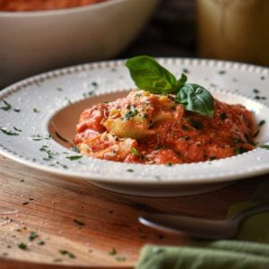 Tortellini with ricotta tomato sauce in a white dish.