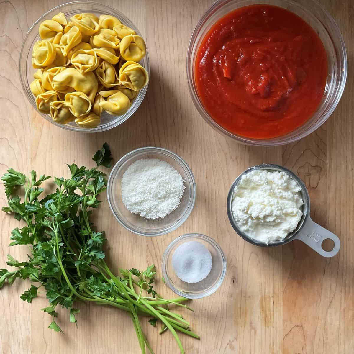 Ingredients to make tortellini on a wooden board.