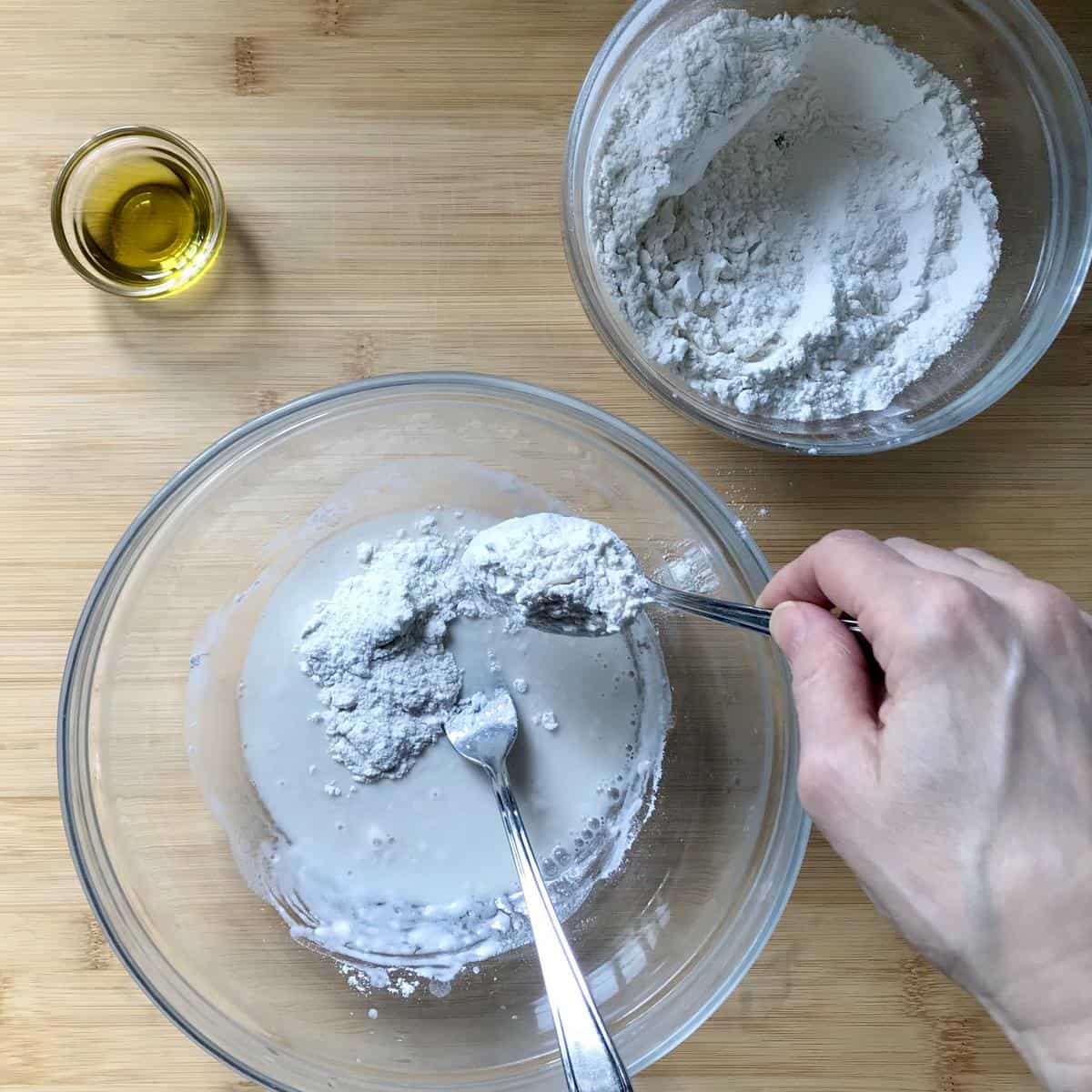 Flour being added to water in a bowl.