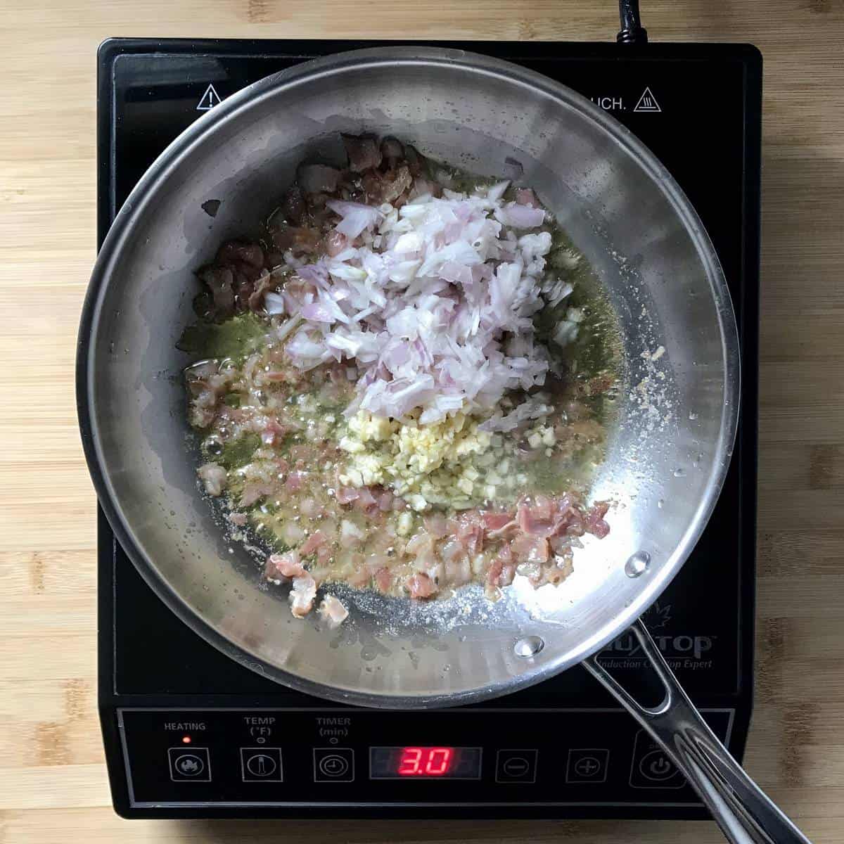 Garlic, onions and pancetta sauteed in a pan.