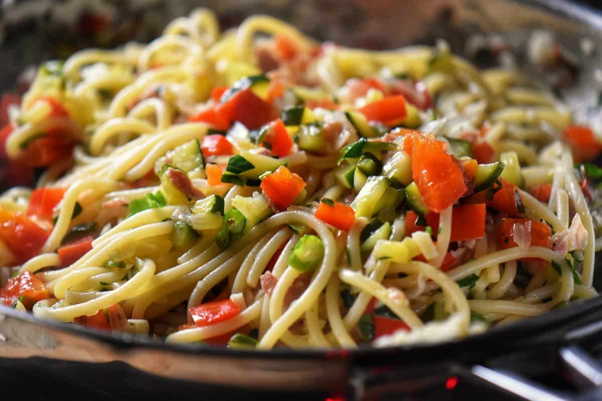 Sauteed veggies and spaghetti in a pan.