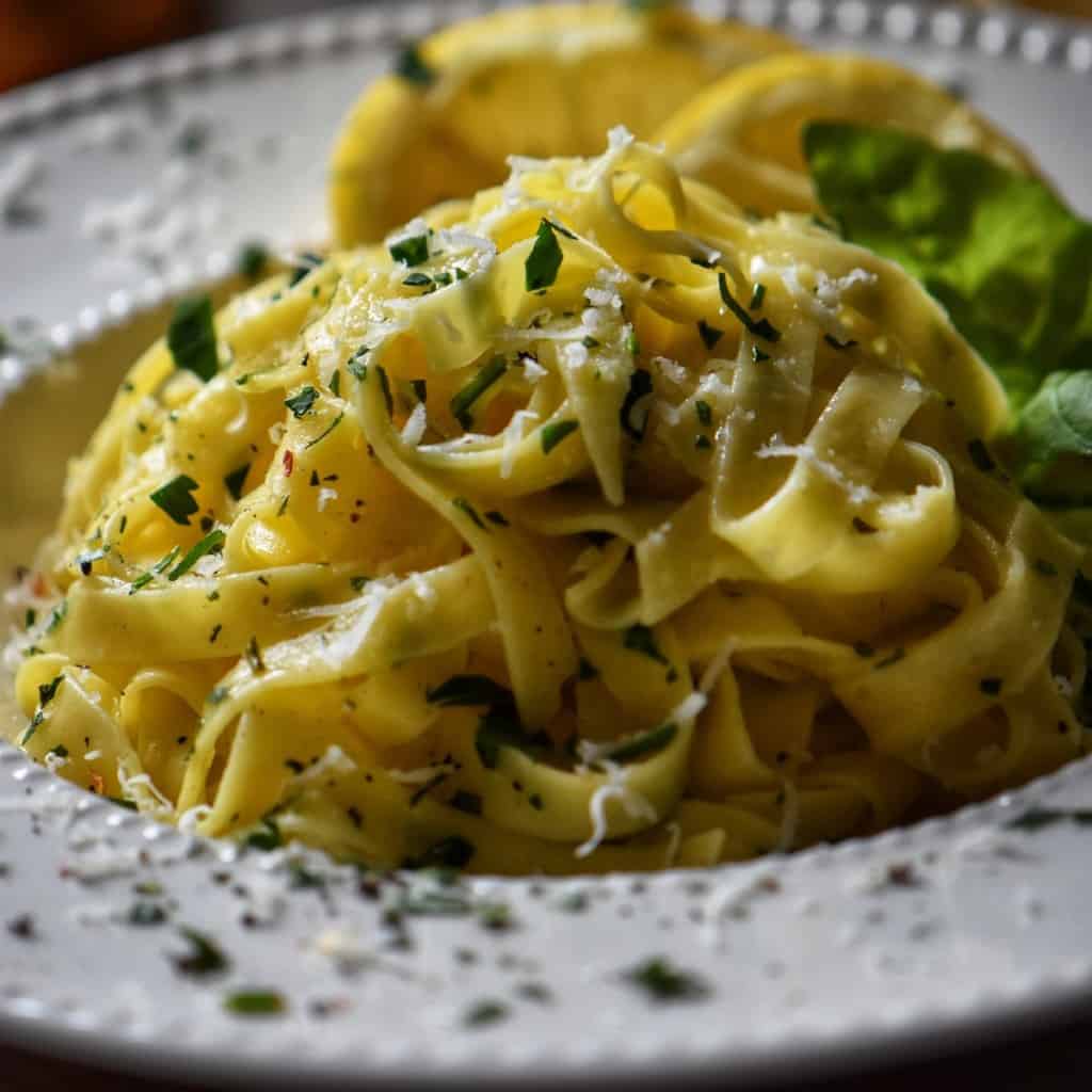 A white dish of fettuccine, garnished with chopped parsley.